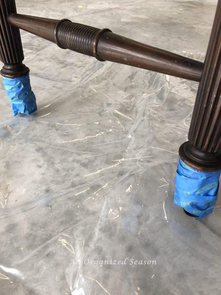 Desk sitting on plastic sheet with metal pieces wrapped in painters tape.