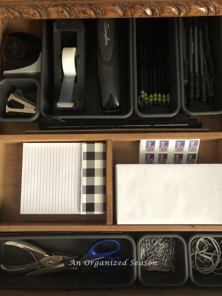 An drawer with storage cubbies for  office supplies. 