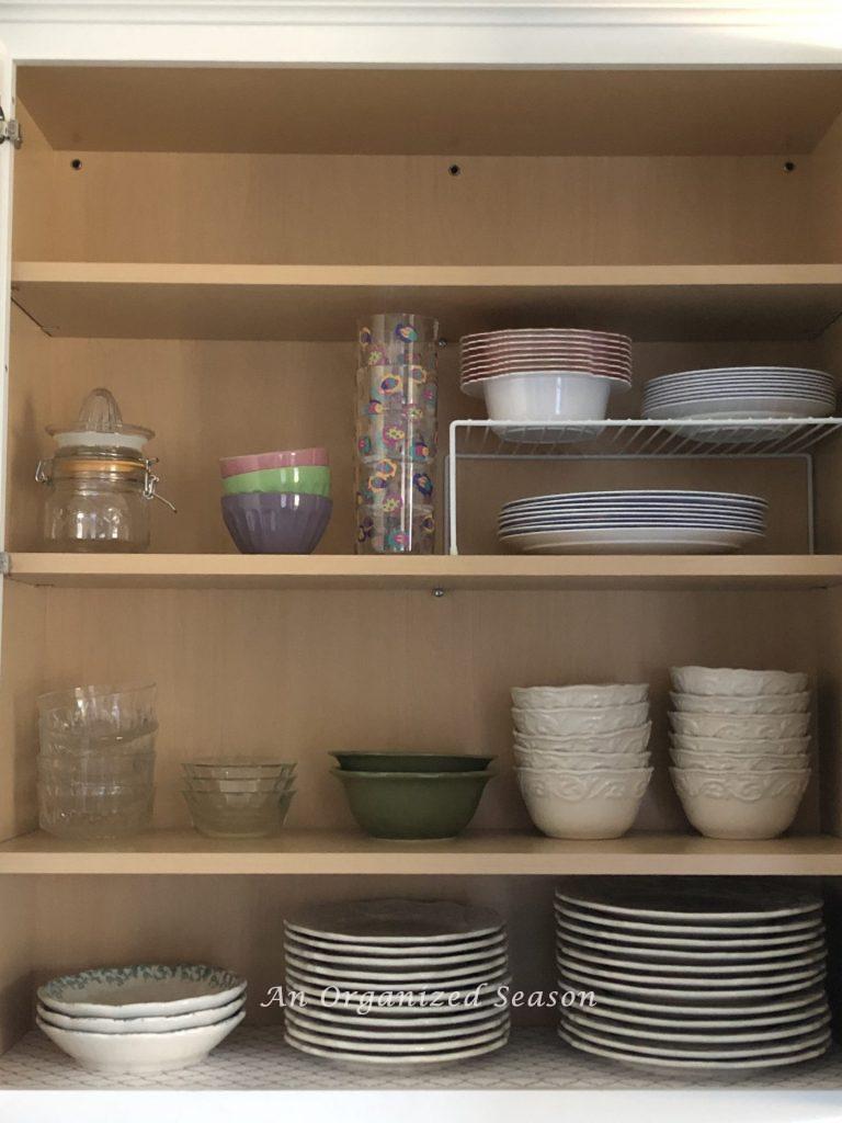 Cabinet with organized plates and bowls showing how I organized my kitchen into zones. 