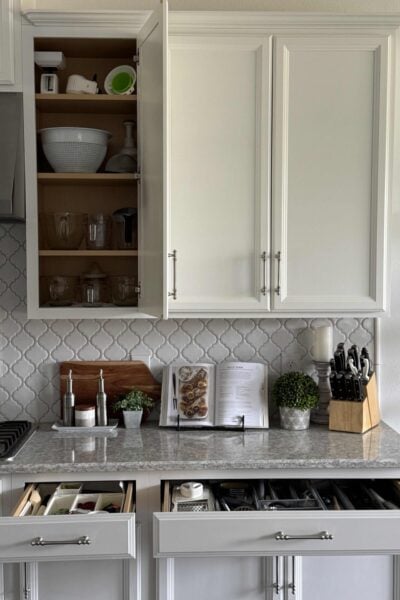 An organized kitchen with an open cabinet and two drawers.