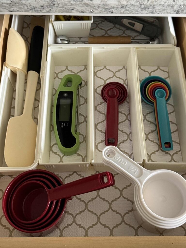 kitchen drawer with organized measuring cups, spoons, thermometer, and spatulas.