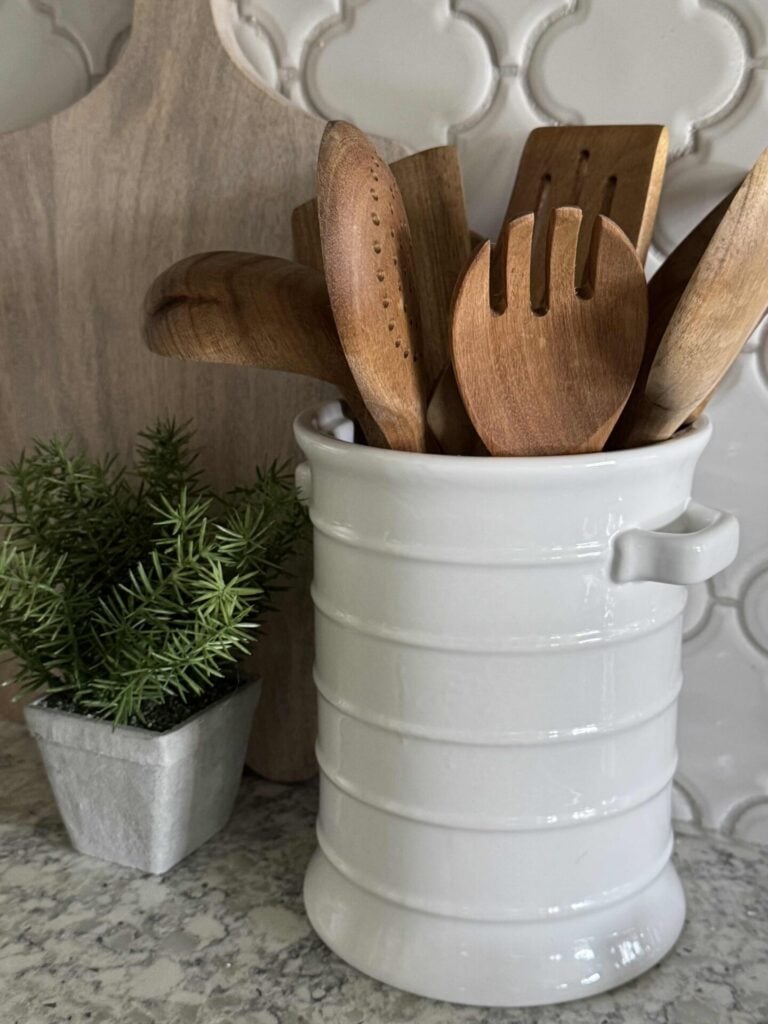 White utensil holder filled with wood cooking utensils.