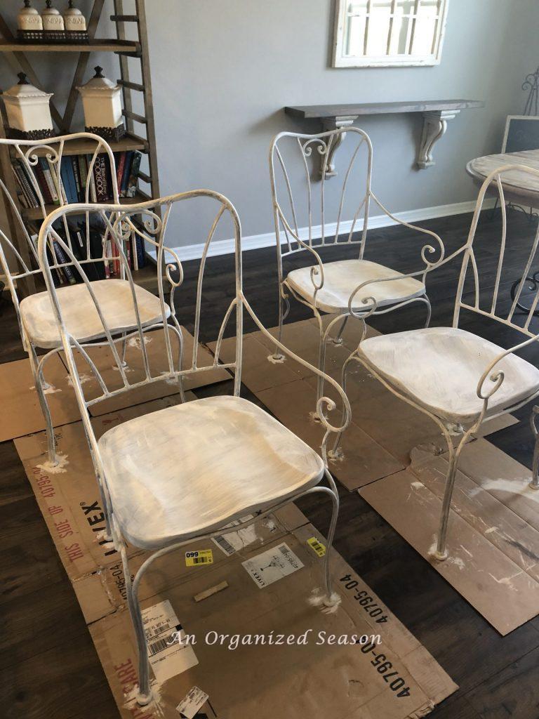 Four chairs being painted white. 