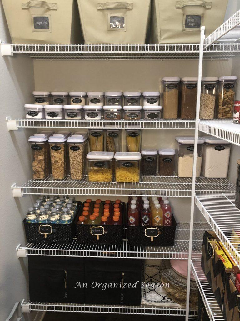 the back wall of my pantry filled with cloth containers holding paper goods and chips to show how to organize your kitchen pantry