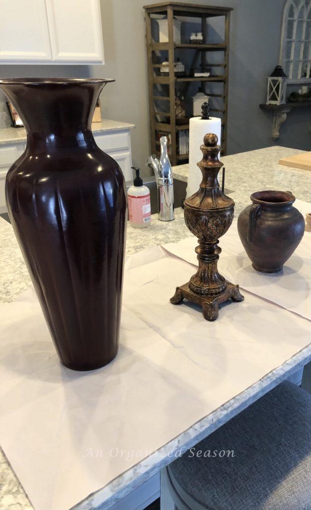 Two brown vases and a brown statue sitting on a kitchen counter. They are old decor items that I will update with paint.