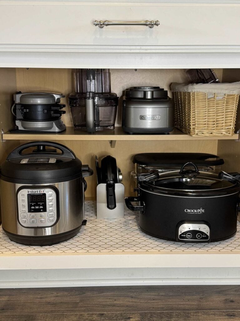 Small appliances organized in a kitchen cabinet. 