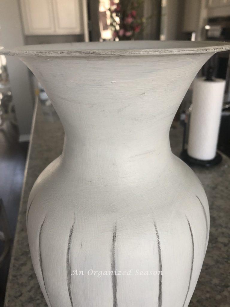 Up-close picture of a vase showing how to update old decor items by painting white and adding dark wax to embellish.