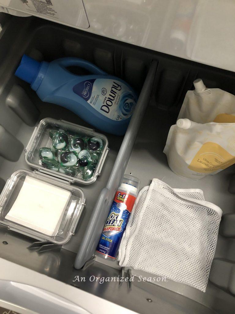 The drawer under my washing machine has Tide pods, downy, stain stick and extra detergent showing how to organize your laundry room