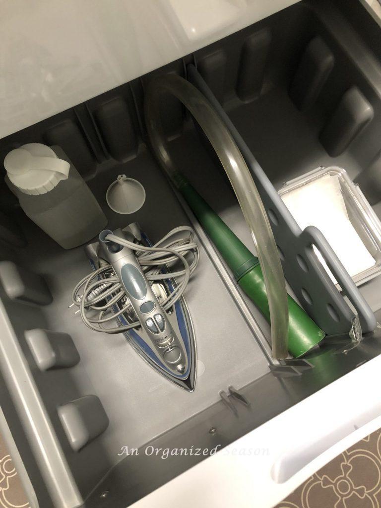 The drawer under my dryer contains dryer sheets, lint hose and ironing supplies showing an example of how to organize your laundry room