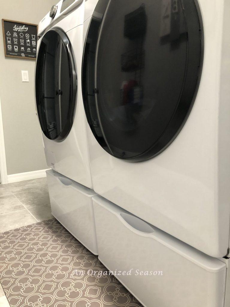 My washer and dryer sitting on top pedestals that provide extra storage so you can organize our laundry room