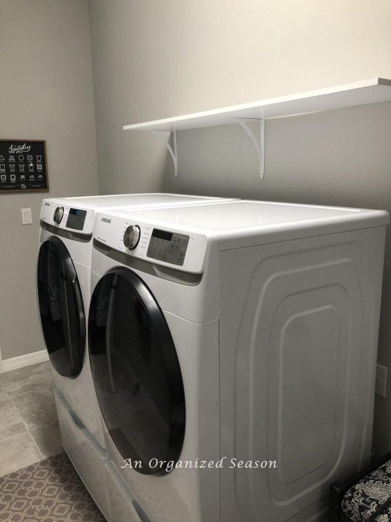 A white shelf above the washer and dryer we added to organize the laundry room