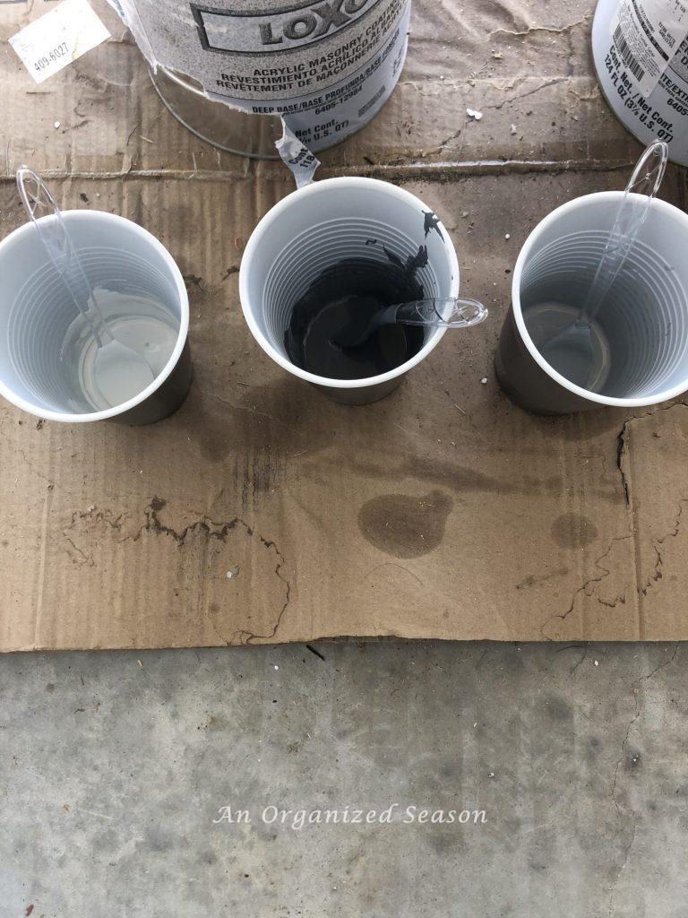 Three plastic drinking cups containing three different colors of paint to be used to build a personalized coat rack. 