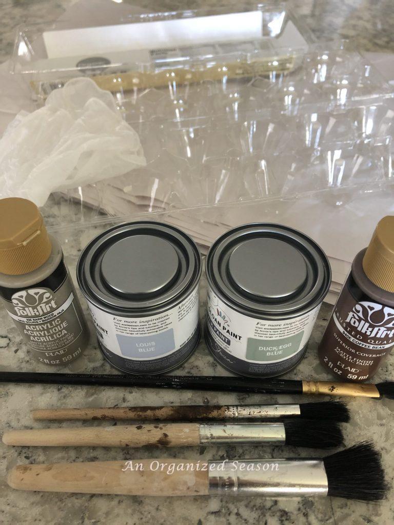 Four colors of paint, brushes, gloves, paper, and egg carton. These are supplies I will use to make realistic eggs for my spring decor.