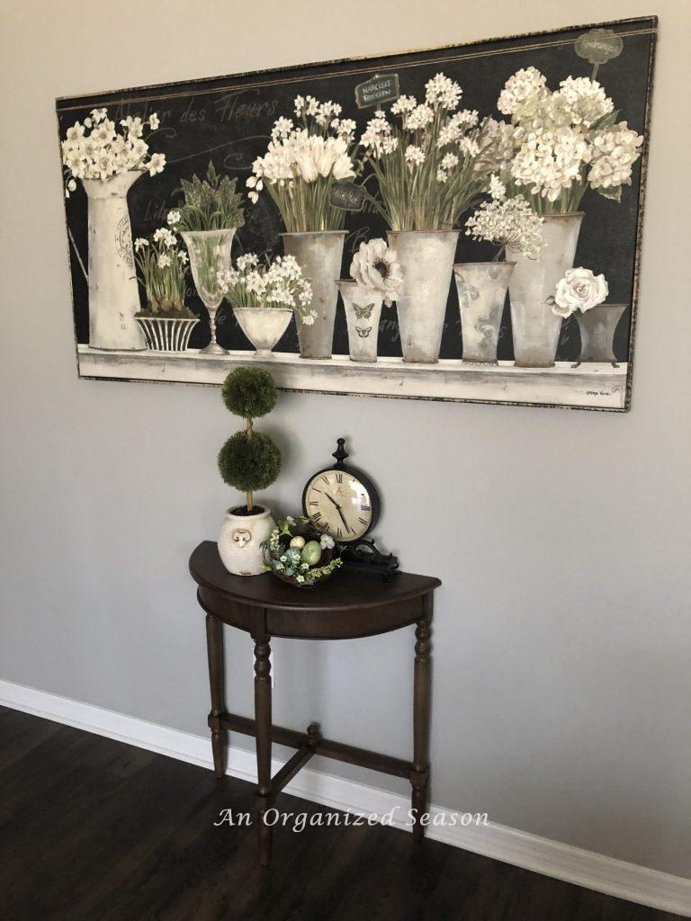 Picture of white spring flowers in white metal pots hanging on a wall.  An example of helpful ideas to brighten spring decor in your home. 