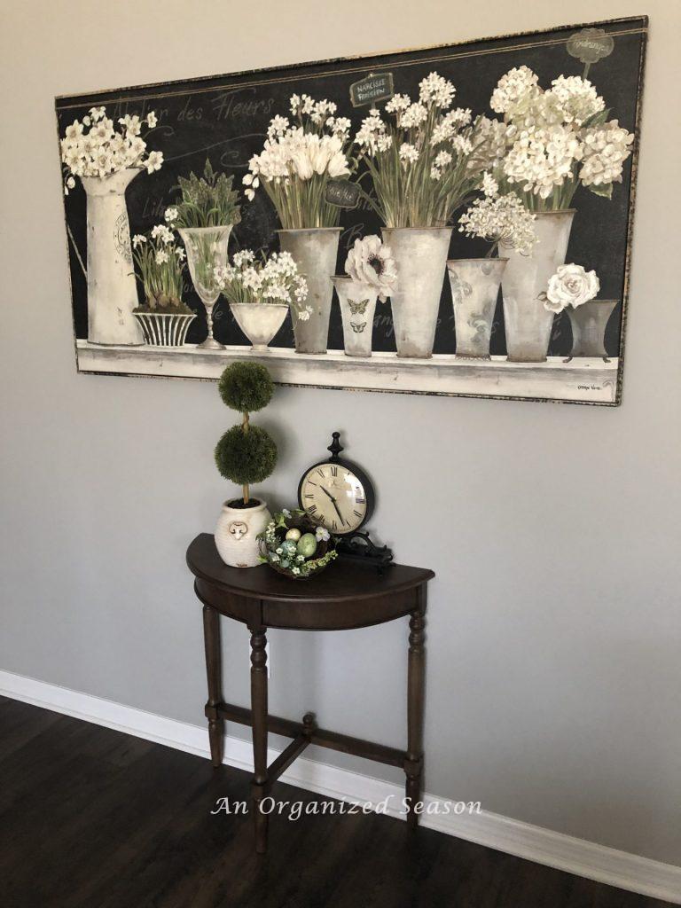 Picture of white spring flowers in white metal pots hanging on a wall. An example of helpful ideas to brighten spring decor in your home.