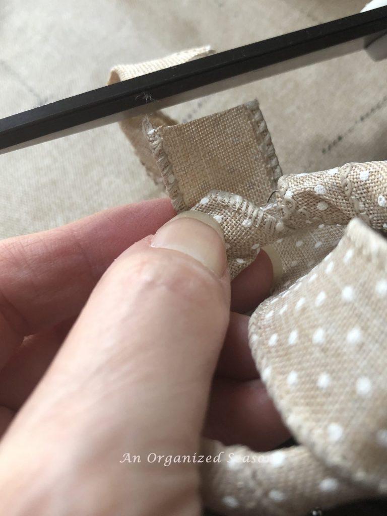 Cutting a piece of ribbon that was wrapped around a plastic shower curtain ring.  Showing step four of how to create an inexpensive floral napkin ring.