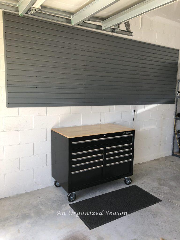 Self adhesive card pocket label adhered to a black storage tub. Card is labeled paint supplies. Fulfilling steps for garage organization.