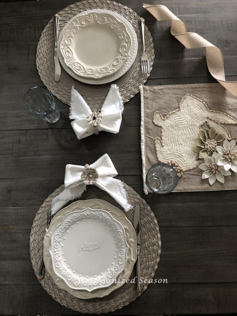 Two place settings on a dining room table using plates that don't match but are the same colors of white and beige. Showing tips for creating a simple Easter tablescape.