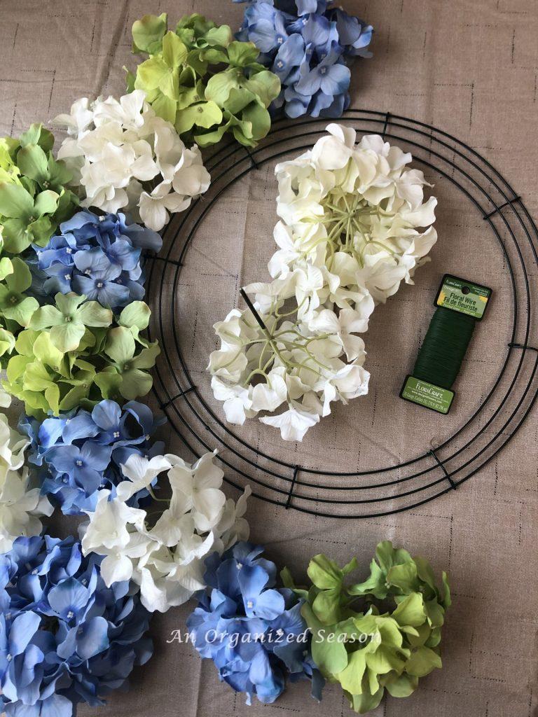 A wreath form, floral wire, and fifteen faux hydrangea blooms in white, blue, and green. Items you need to gather for step one of how to make a hydrangea spring wreath.