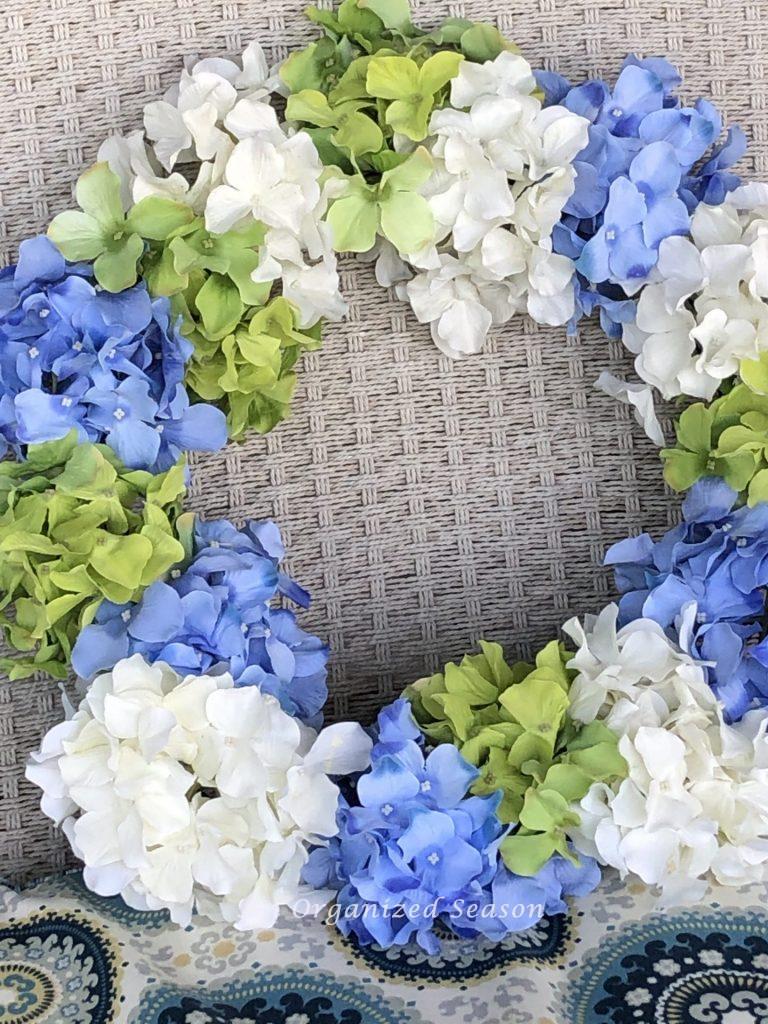 A tri-colored wreath made of hydrangea blooms. Adds decor so you can enjoy your porch this Spring. 