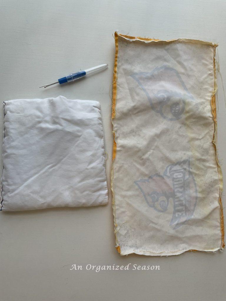 A cornhole bag that has the outer layer of fabric removed and a seam ripper next to it.  Step twelve for steps to transform a worn out cornhole set.