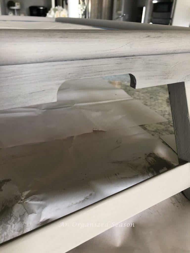 A gray tray with black wax that has been applied and then wiped into the top half. Showing step eight for how to makeover a breakfast in bed tray.