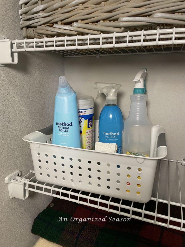 A white plastic tub sitting on a wire shelf that's filled with cleaning products. An idea on how to organize linen and cleaning closets. 