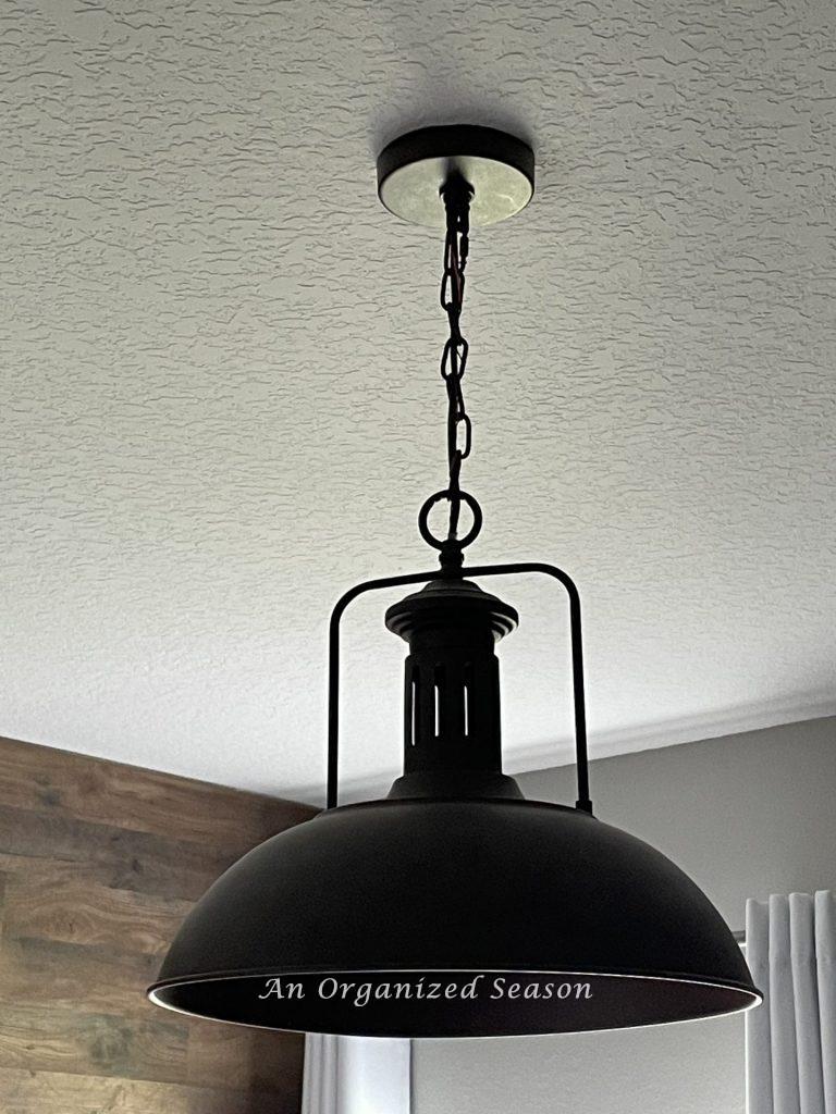A brown rustic pendant light hanging from a ceiling mount.  Showing step two for how to makeover a bedroom into a rustic retreat. 