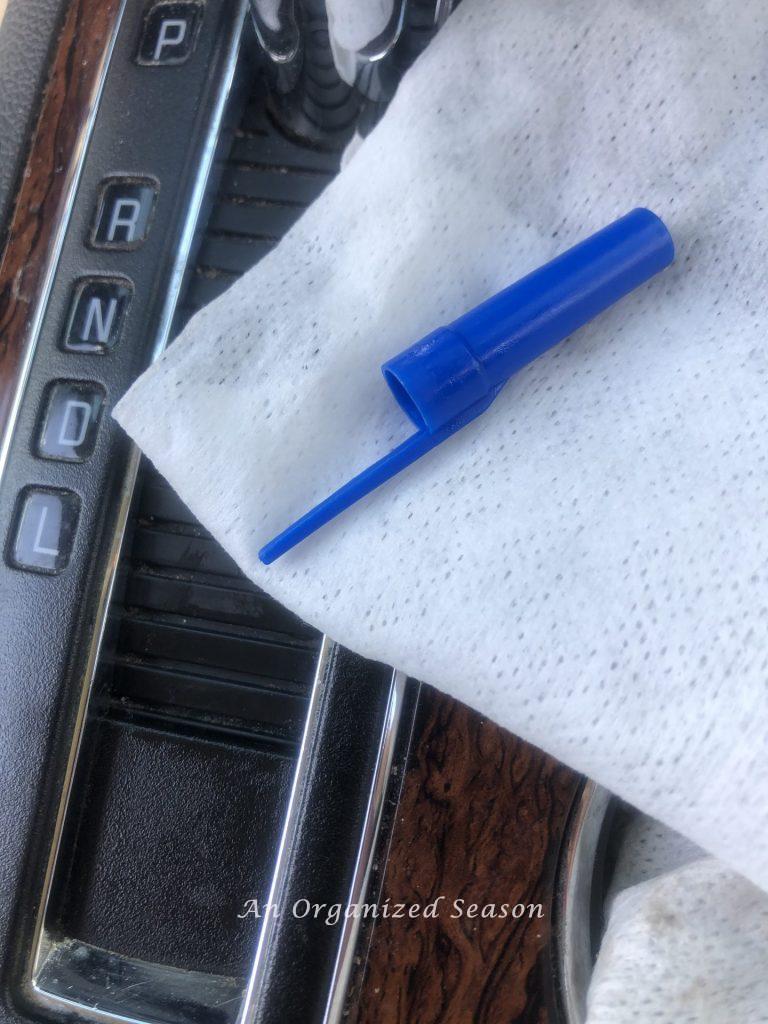 The cap of an ink pen sitting on top of a car cleaning wipe that was used to clean small indentations in the car. An example of tips to clean and organize your car.