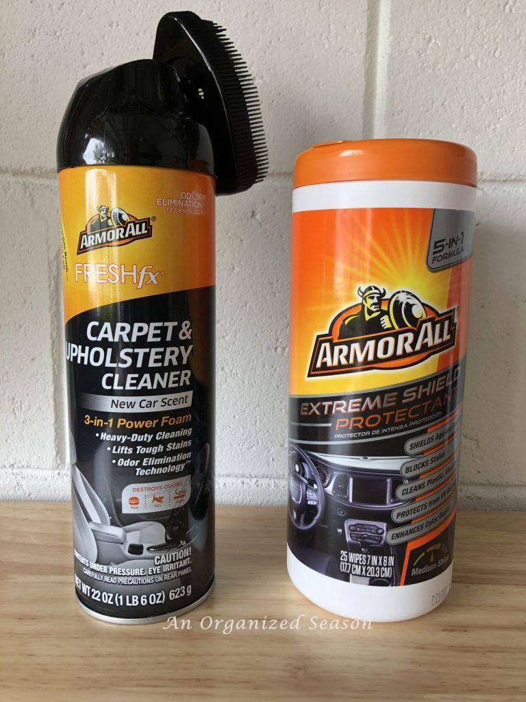 A bottle of Armor All cleaning wipes and a can of Armor All carpet and upholstery cleaner for cars, sitting on a wood table. Tips for products to use when you organize and clean your car.