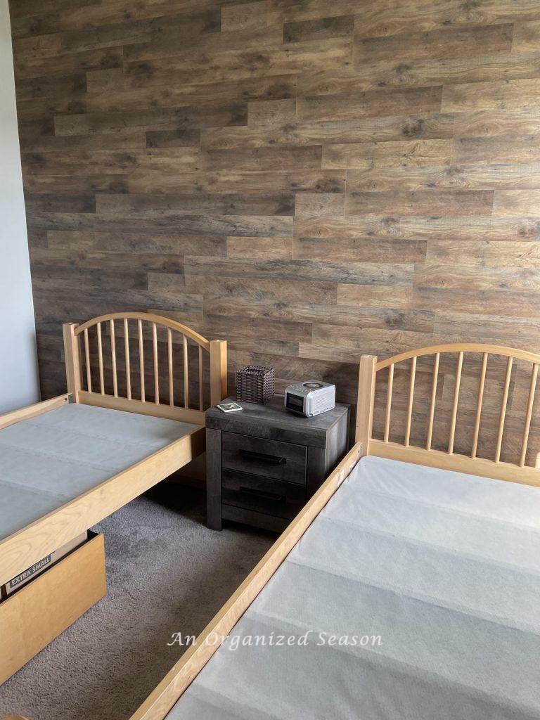 picture of two twin beds in front of vinyl flooring feature wall