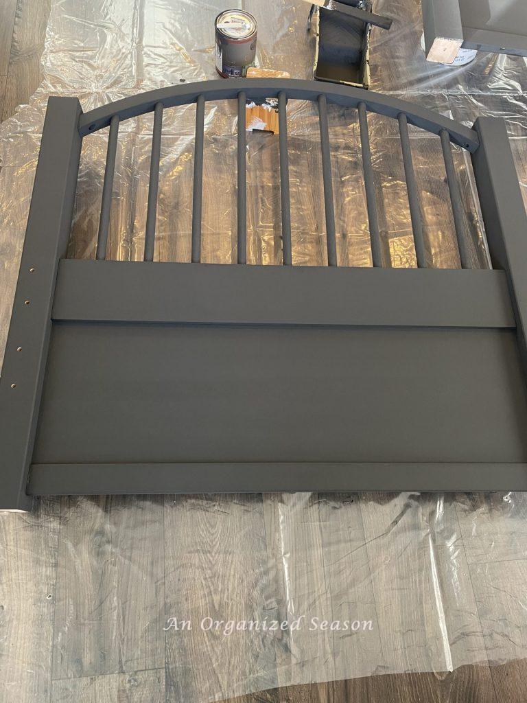 A twin bed headboard with two coats of black chalk paint.  Showing step six for how to refinish twin beds with chalk paint.