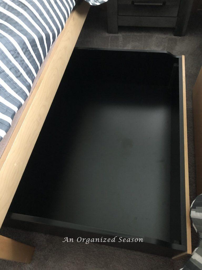 An empty storage drawer under a bed. 