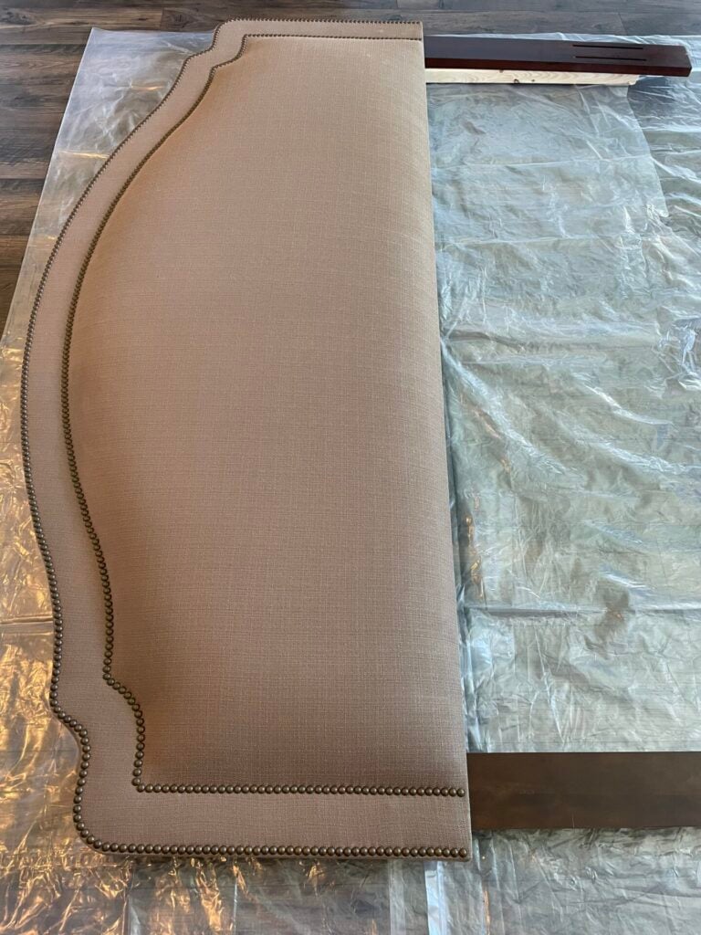 Olive drab upholstered head board laying on plastic.