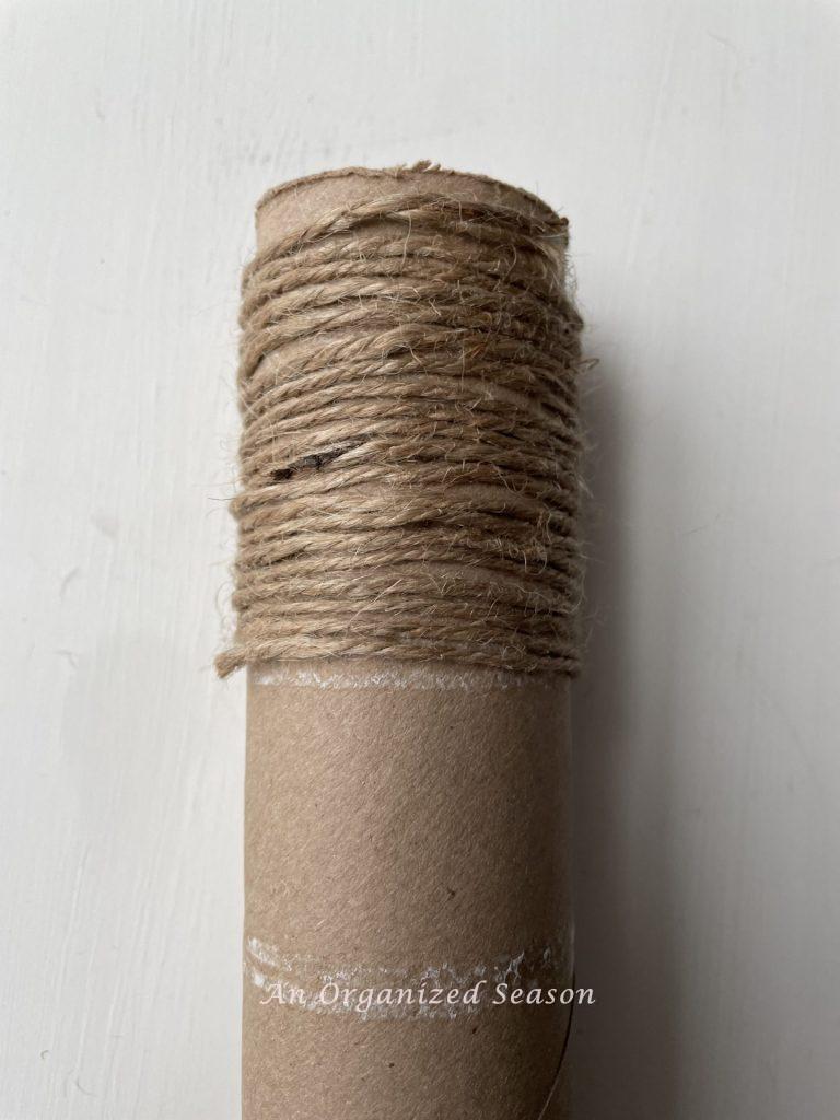 Jute twine wrapped 2o times around a paper towel cylinder showing how to make two types of twine pumpkins.
