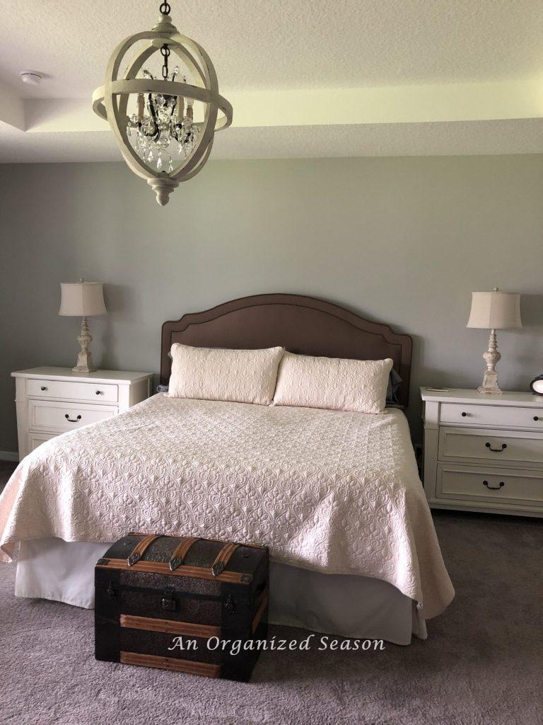 Master bedroom with green headboard that does not match gray walls.