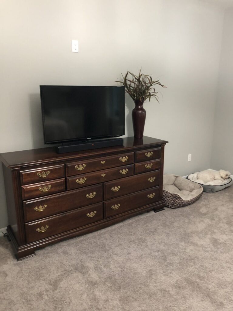 A brown dresser with TV on top, 