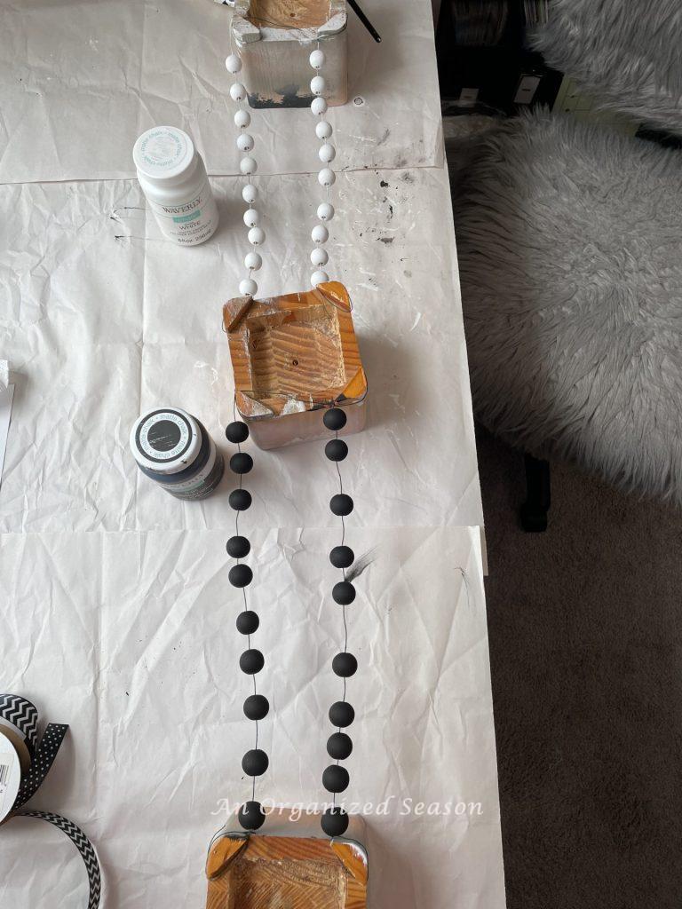 Wood beads strung on a wire and painted black and white. Step one for how to make a Halloween wood bead garland.
