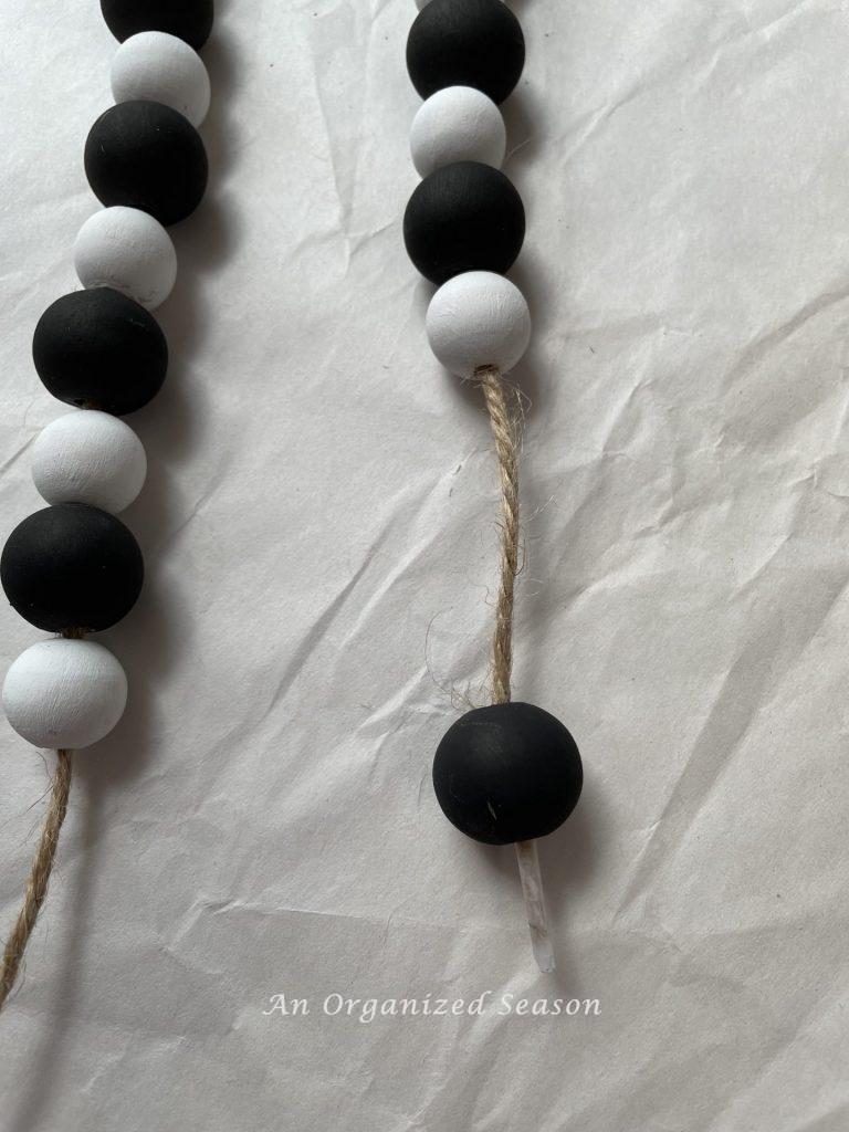 Black and white alternating wood beads strung on jute twine. Step three for how to make a Halloween wood bead garland.