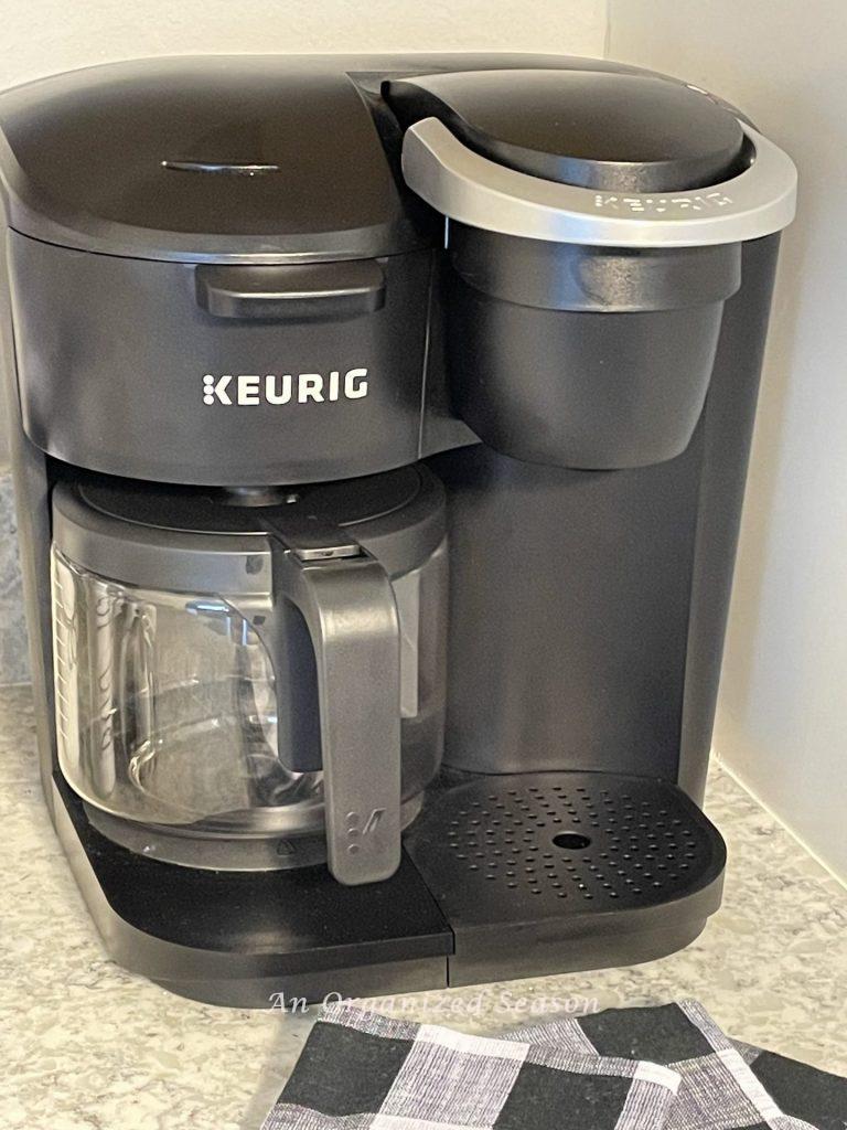 A Keurig coffee maker sitting on a kitchen counter showing steps to make a fall coffee bar.