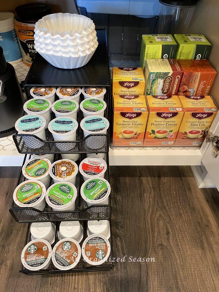 A coffee organizer stocked with coffee pods next to several boxes of flavored teas showing steps tp make a fall coffee bar.