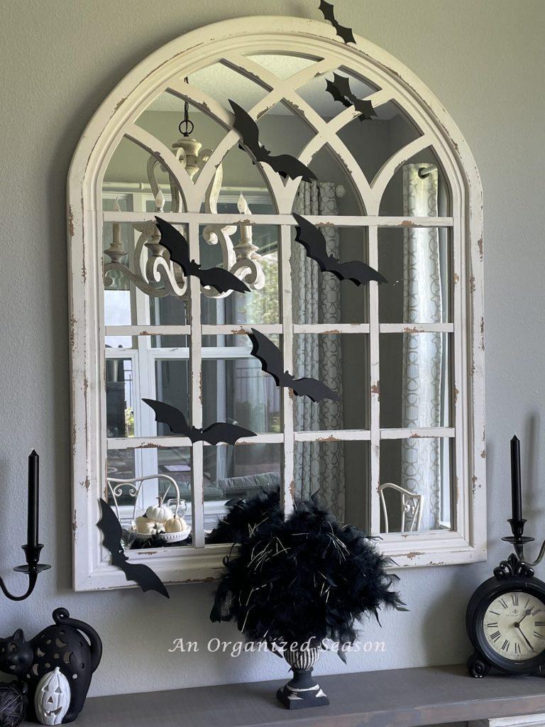 A large white, chippie mirror covered  with black bats in an eat-in kitchen. An example of inexpensive of inexpensive Halloween decor for your kitchen. 