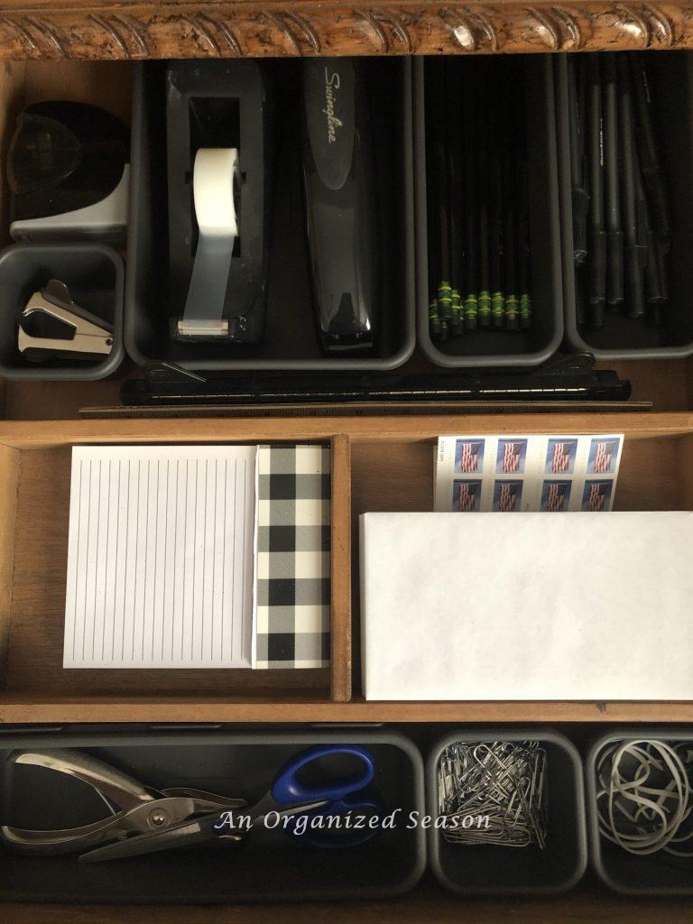 An organized desk drawer with compartments for office supplies like, pencils, paperclips scissors, etc. An example of how to set Fall home organization goals. 