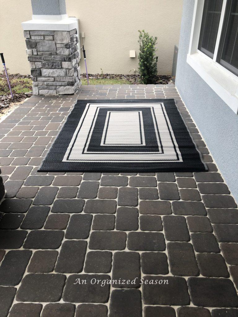 A black and white rug on a porch, step two for how to decorate a porch for Fall.