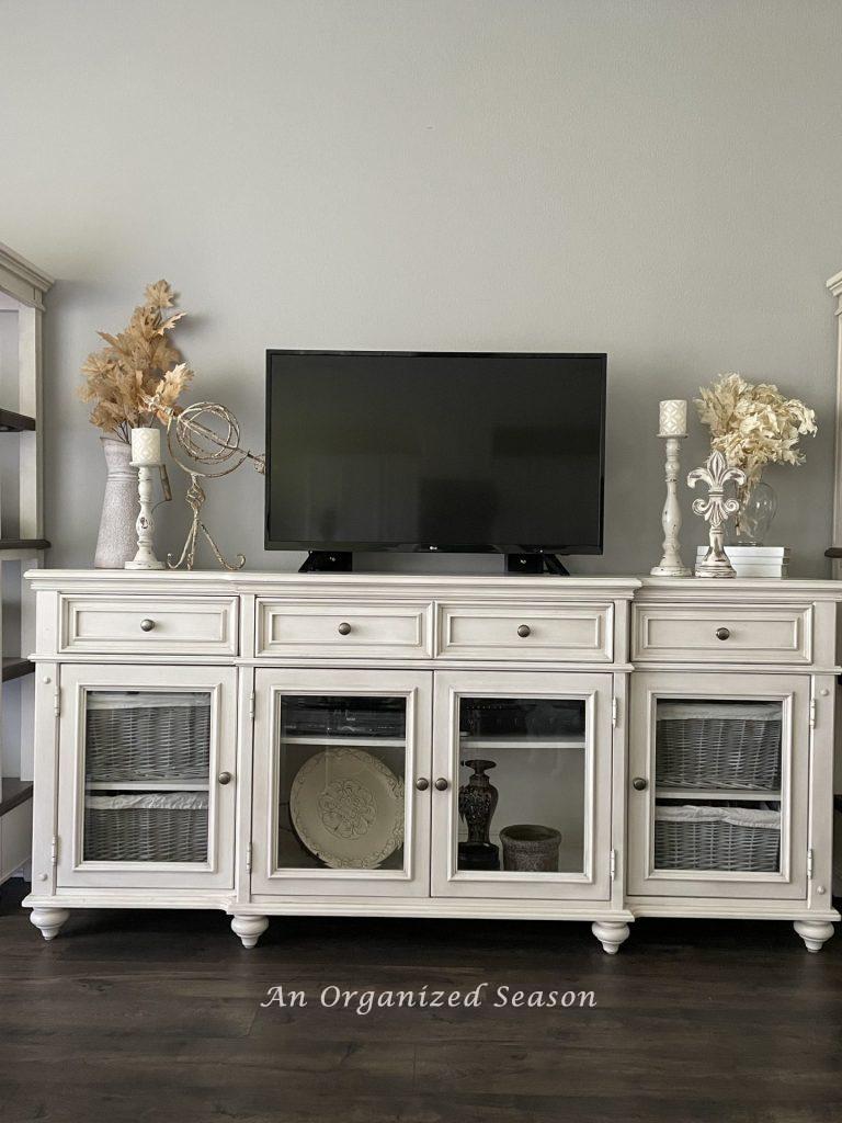 An off white console table with drawers and cabinets to help you maintain an organized living room.