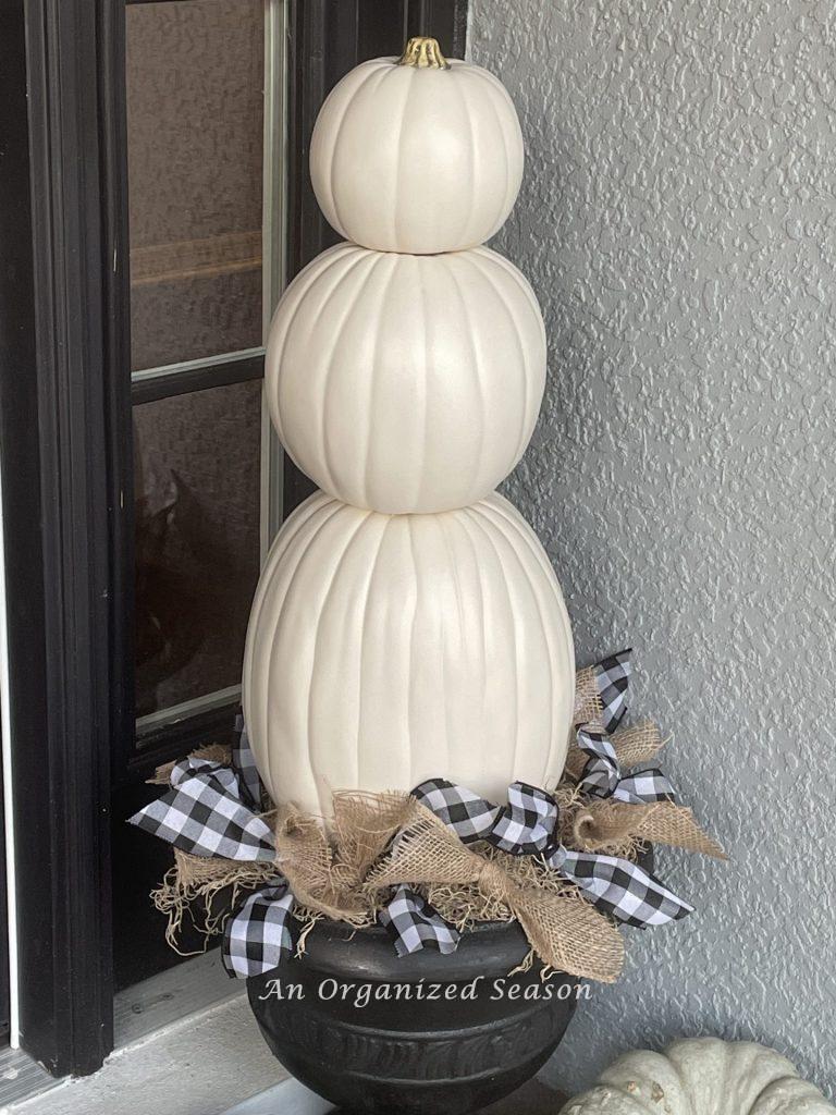 A black urn filled with a three-tiered white pumpkin topiary. An example of how to decorate your porch for Fall.