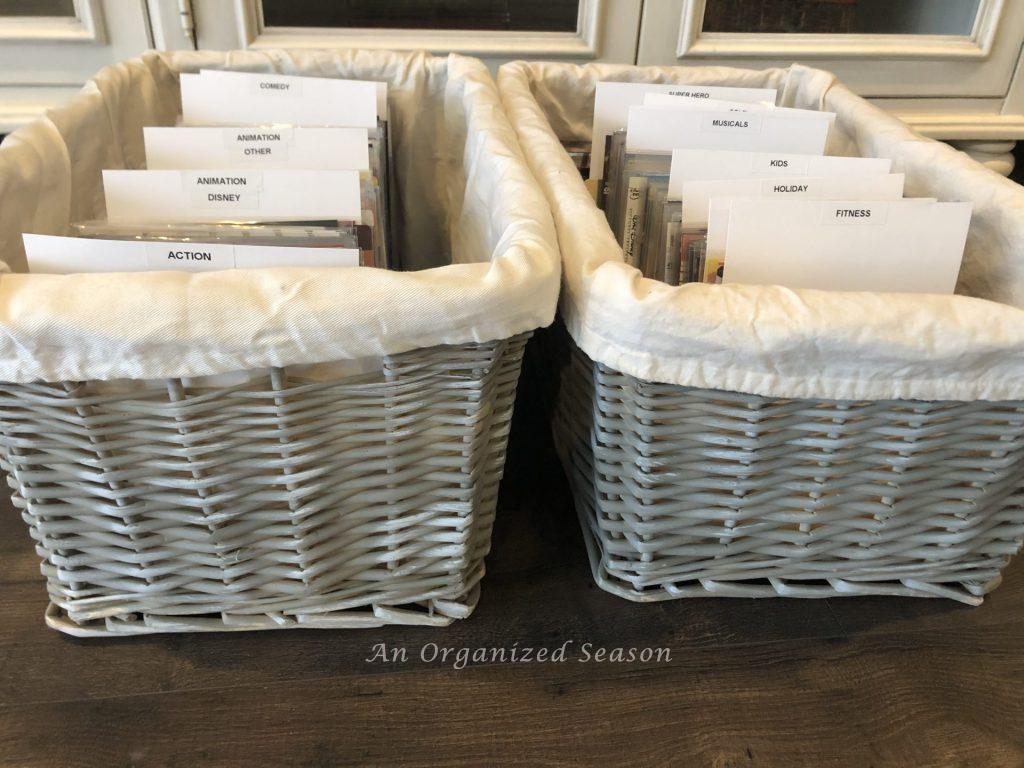 Two wicker baskets filled with DVD sleeves with genres separated by labeled cardstock dividers.