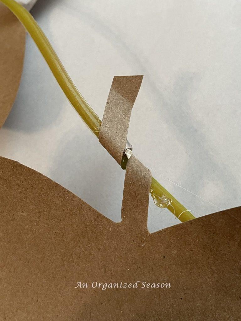 A paper leaf stem wrapped around hot glue on a plastic garland.