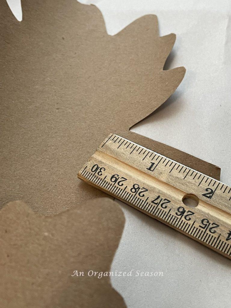 A ruler measuring the stem of a paper leaf to be used on a garland. 