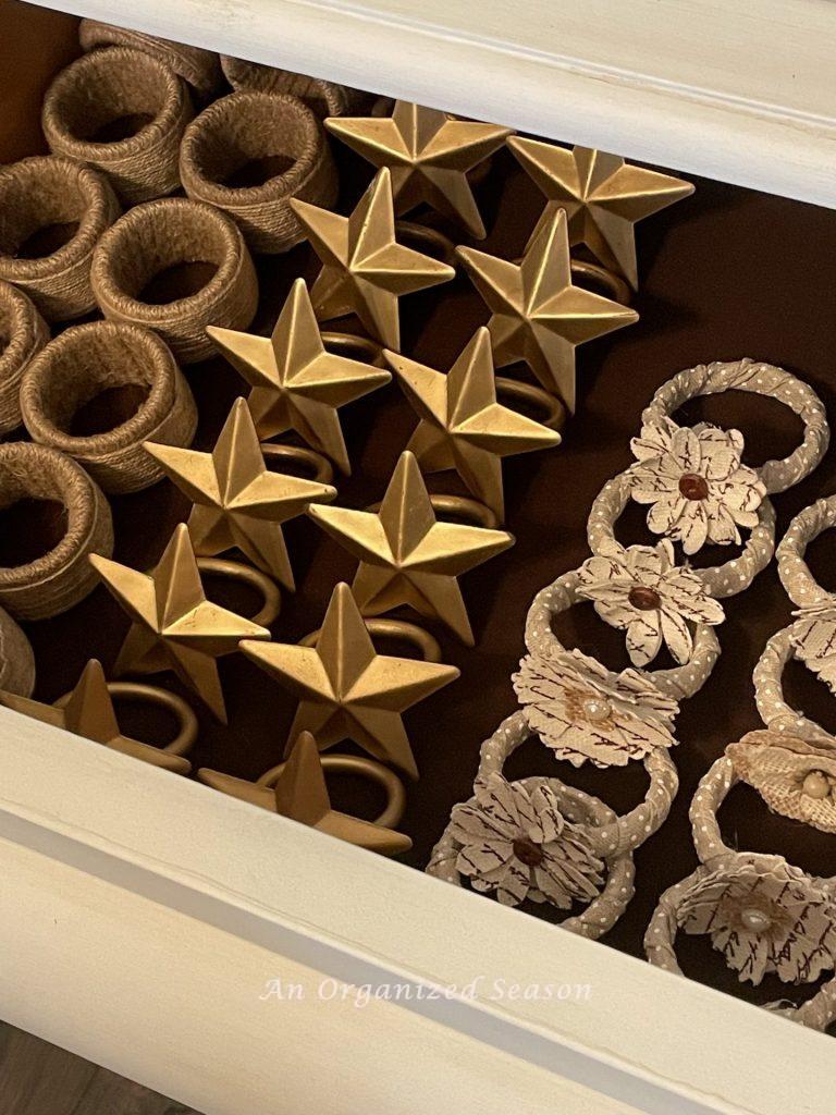 An open drawer in a china cabinet filled with napkin ring holders. Showing how to organize your dining room for easy entertaining. 